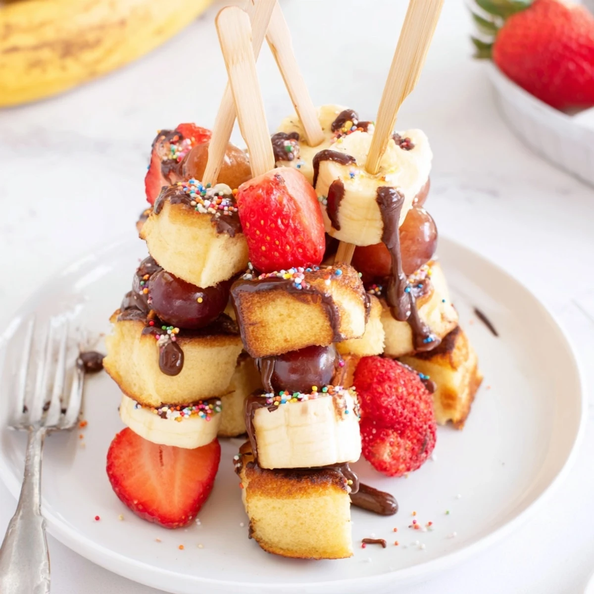 Delicious Chaos Cake Pancake Skewers stacked with fresh fruit and cake cubes.