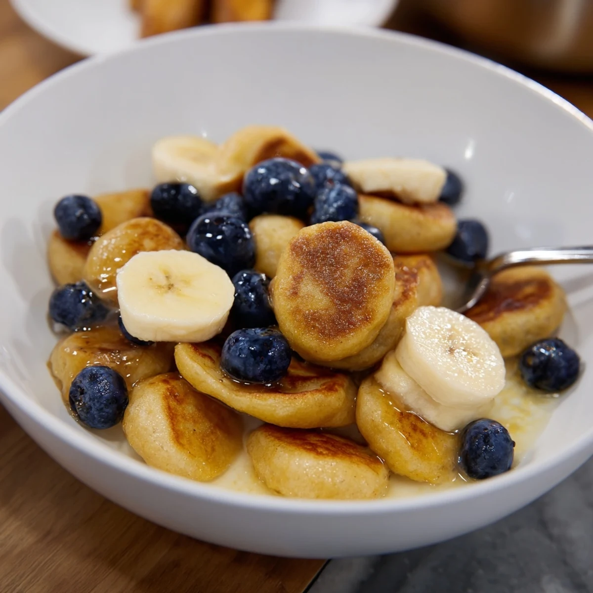 Crispy and fluffy Mini Pancake Cereal drizzled with honey and accompanied by fruit.