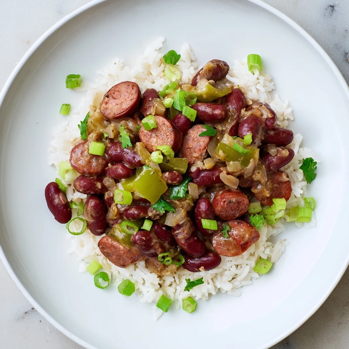 Fragrant Red Beans & Rice served on fluffy white rice, with visible green onion garnish and hot sauce.