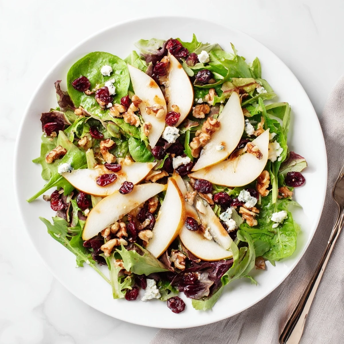 Fresh sliced pears and crumbled Gorgonzola cheese top a bowl of mixed greens, walnuts, and dried cranberries, drizzled with honey-balsamic vinaigrette.