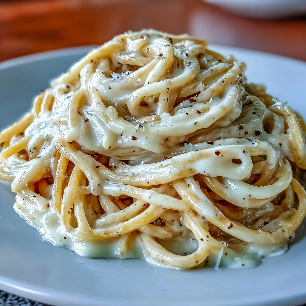 Close-up of Cacio e Pepe showcasing toasted black pepper flecks and glossy, cheese-coated pasta.