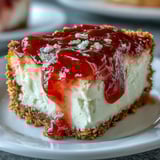 Guava Cheesecake with a vibrant pink swirl on a crisp Maria cookie crust, garnished with fresh mint and a slice of guava.