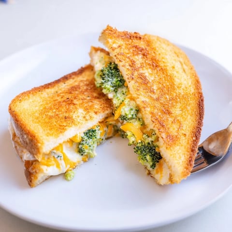Golden brown air fryer broccoli cheddar stuffed grilled cheese with melted cheese oozing out.