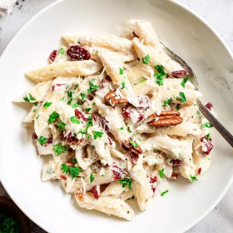 Rich Thanksgiving Cranberry Cream Cheese Pasta garnished with vibrant parsley and buttery nuts.  