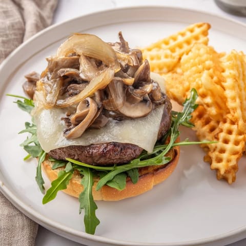 Golden-brown waffle fries accompany a juicy Mushroom Swiss Burger, a classic American comfort food combo.