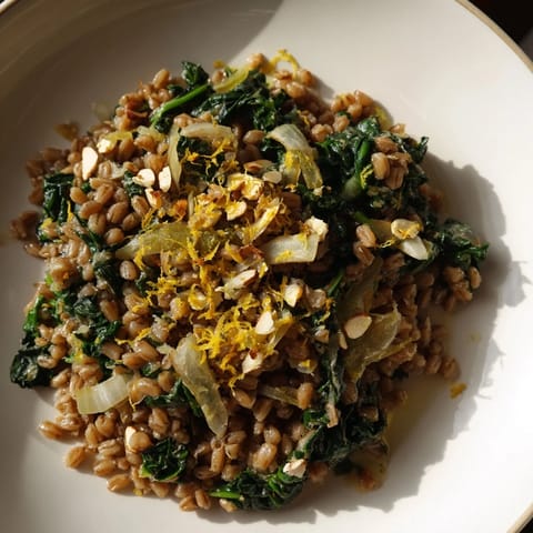 A vibrant close-up showcasing the delicious ingredients in this warm farro & greens pilaf dish.