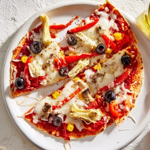 A close-up view of a freshly baked tortilla pizza featuring colorful pantry toppings and melted mozzarella.