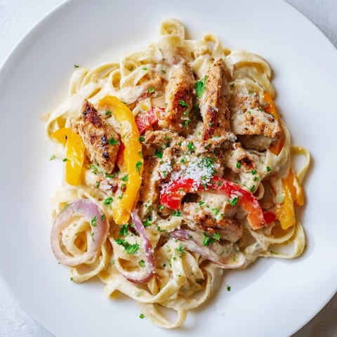 Sizzling skillet of Cajun Chicken Pasta topped with Parmesan, offering a rich, savory aroma.
