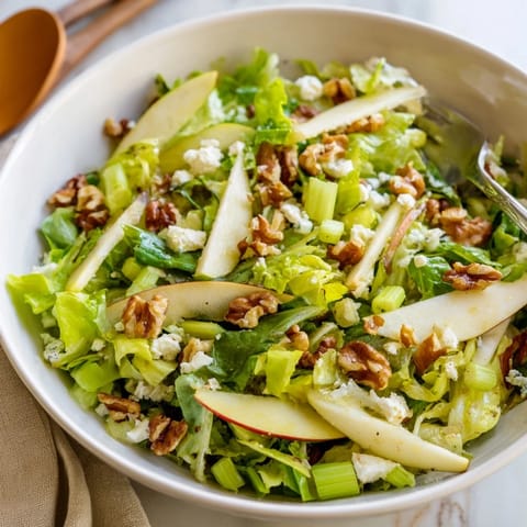 Apple and Walnut Salad topped with crumbled blue cheese, ready to serve as a refreshing winter side dish alongside roasted chicken.