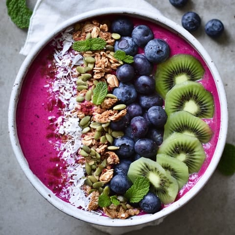 Thick Beet and Berry Smoothie Bowl garnished with kiwi, pumpkin seeds, and coconut.  