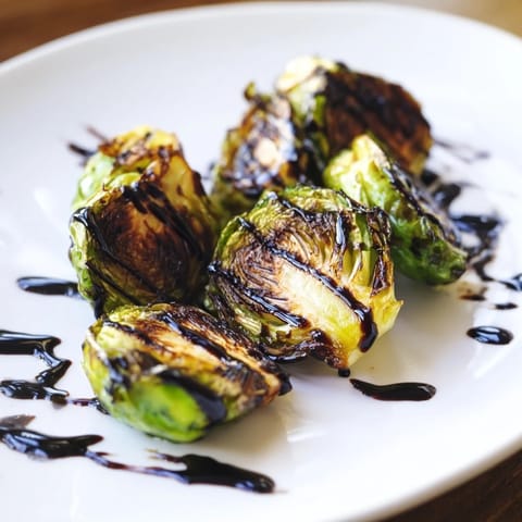 Freshly roasted Brussels sprouts drizzled with sweet balsamic glaze, served warm as a vegetarian side.  