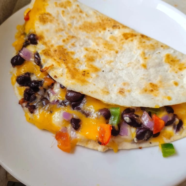 A crispy, delicious Black Bean Quesadilla with optional toppings—cilantro, sour cream, and salsa—on a plate.