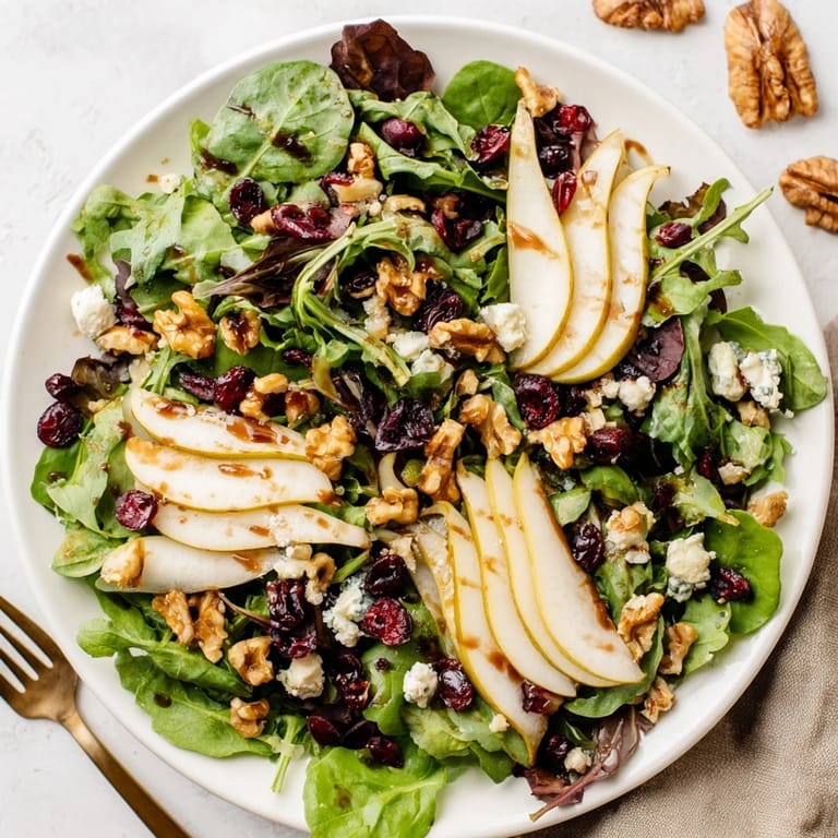 Vibrant mixed greens with sweet pear wedges, tangy Gorgonzola, and crunchy walnuts, ready to serve as a refreshing vegetarian side salad.