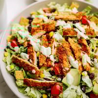 A vibrant Crunchy Taco Chicken Salad topped with crushed shells, seasoned chicken, and a creamy lime dressing.