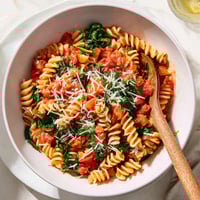 Fork twirling through al dente rotini in a single pot, loaded with juicy tomatoes and wilted spinach.