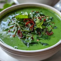 Creamy coconut Spinach Coriander Lemongrass Soup steaming in a white bowl, garnished with fresh cilantro and chili slices for color.