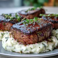 Golden-brown venison steaks with a seared crust sit atop creamy swede mash flecked with caraway seeds.