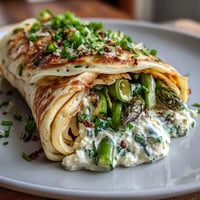 Golden buckwheat crepes filled with creamy herbed cheese and vibrant spring vegetables, a perfect vegetarian brunch option.
